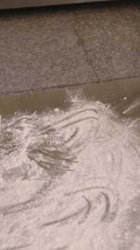 Vertical video: Shifting bowl then pouring flour, chef in apron prepping bakery counter for dough