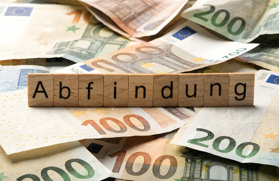 Wooden blocks with the german word abfindung on a pile of euro banknotes