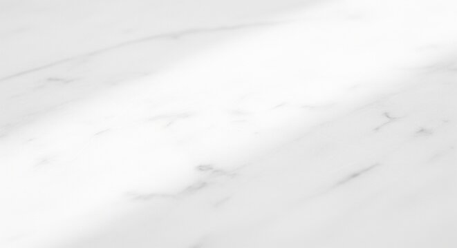 A bright, overexposed view looking across a smooth white marble surface with faint grey veins and a strong light glare coming from the top corner