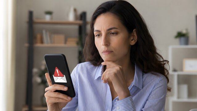 Woman reading scam email alert on smartphone at home