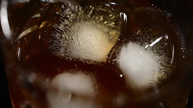 Extreme close-up top view of ice cubes spinning in cocktail glass, frozen crystal blocks rotating in liquid, detailed macro shot of swirling ice, clear transparent cubes moving in circle, cold refresh
