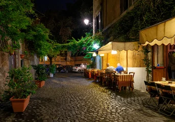 Night cozy old street with tables of restaurant in Trastevere in Rome, Italy. Trastevere is rione of Rome, on west bank of Tiber in Rome. Architecture and landmark of Rome © Ekaterina Belova