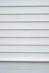 Fototapeta premium Vertical close up of white painted lap siding with smooth horizontal boards, slight wood grain, small cracks, minor marks, a starter board, and a water table board