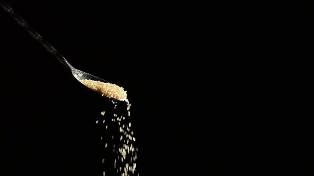 Brown cane sugar pouring from spoon on black background, slow motion falling grains, sweet crystalline texture, cocktail preparation concept, professional bartending, natural sweetener for drinks