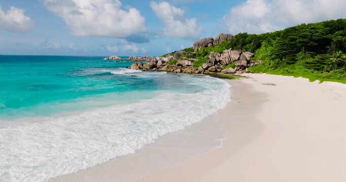 Scenic view of a tropical beach with turquoise water, white sand, and dramatic granite rock formations. Seychelles, La Digue.