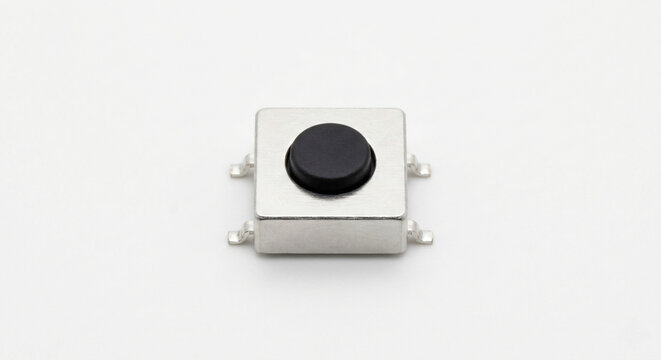 Extreme macro of a bare tactile microswitch with a black push button and silver housing, isolated on white.