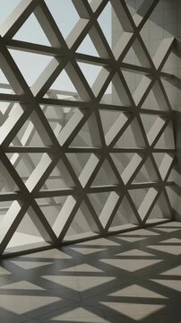 Geometric lattice structure of a contemporary architectural window casting triangular shadows on the floor, creating a rhythmic and abstract light and shadow pattern