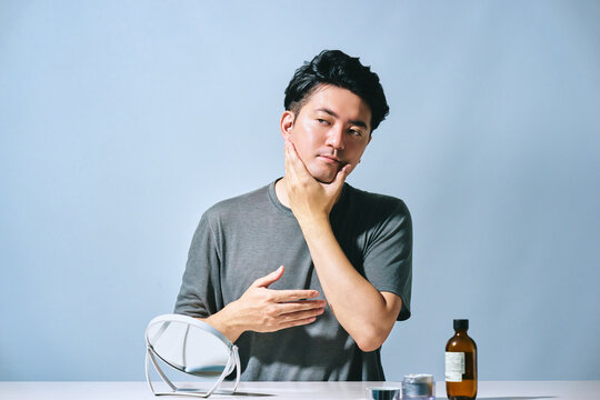 爽やかで清潔感のある30代の日本人男性が顔に触れてスキンケアをするスタイリッシュな美容のイメージ