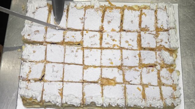An overhead shot captures a chef cutting the celebration cake into small even slices, the bird's-eye view revealing the precise pattern needed to serve everyone at the party event.
