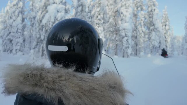 Experience the thrill of snowmobiling through the breathtaking snowy landscapes of Akaslompolo, Lapland Finland. Towering snow-covered trees glisten under a bright blue sky.