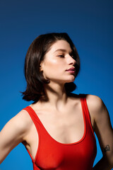 Fototapeta premium Beautiful young woman in a striking red top displays her glowing skin and confidence.