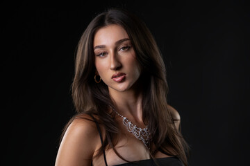 Naklejka premium Female model with long hair wearing a sparkling necklace in a studio portrait