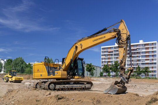 Nancy, France - June 13th 2026 : View on a yellow crawler excavator CAT 323 with a single drum roller Bomag behind for earthworks on a construction site.