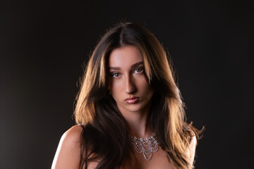Naklejka premium Female model posing with glamorous style and elegant jewelry on a dark background