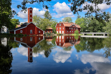 Obraz premium Historic red wooden buildings reflected in the river at Strömfors Ironworks in Loviisa, Finland