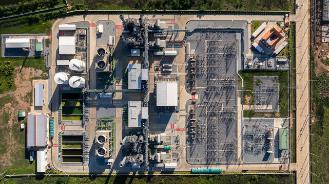 Aerial view combined cycle power plant with cooling tower and substation under blue sky, Industrial infrastructure of electric power station, exhaust stack and cooling systems.