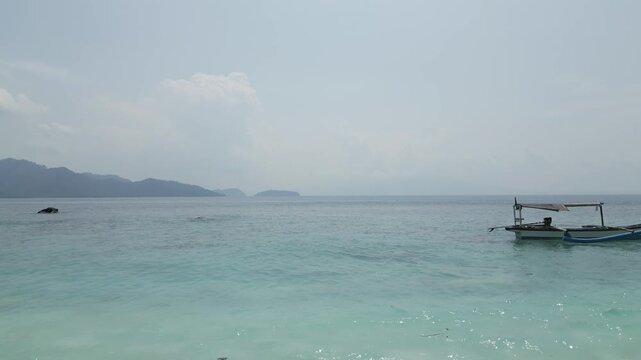 Aerial Pan From Outrigger Boat To Open Sea And Hazy Mountains