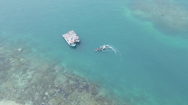 Top Down Aerial Of Boats Over Coral Reef With Wake In Clear Water