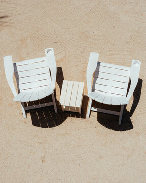 Two White Beach Chairs with Small Table on Sand