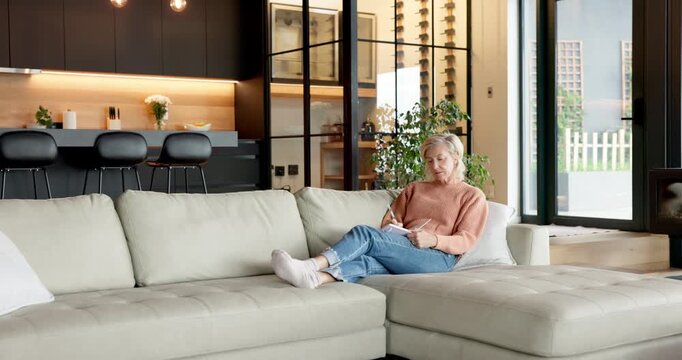 Woman, relax and writing in home with notebook, planning and journaling for self reflection. Thinking, mature person and notes at house with diary, motivation and daily checklist for stress relief