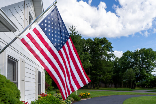 American Flag Flying on White House Exterior with Suburban Neighborhood