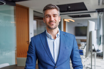 Fototapeta premium Confident businessman smiling, standing in modern office, portraying leadership, professionalism, and corporate success