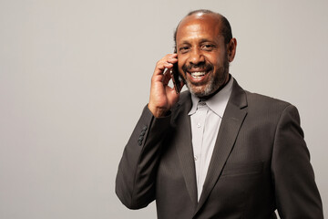 Smiling middle-aged Black man in a suit talking on a cellphone