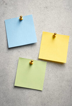 Three Colorful Sticky Notes Pinned to a Textured Surface