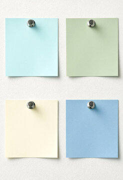 Four Pastel Sticky Notes Pinned to a Textured Surface, Flat Lay Composition