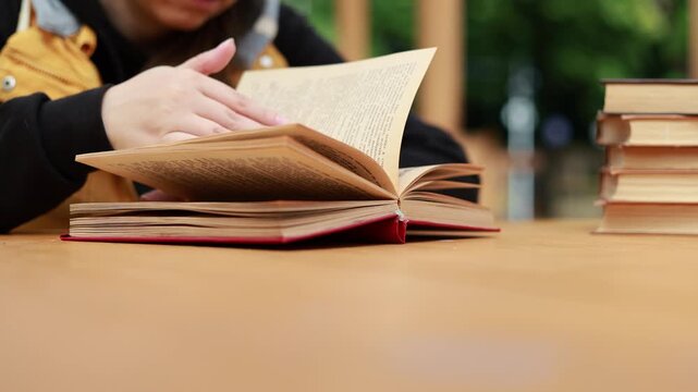 Young woman reading open book on desk. Student enjoying education and literature study. Academic learning process at home or library. Knowledge development, research and hobby concept.