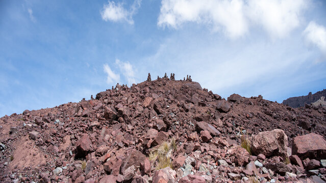 Rock cairns and stone balancing structures for meditation near a green glacier lagoon in the Andes.