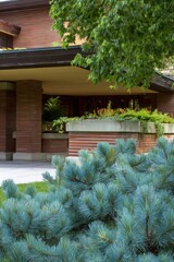 Fototapeta premium Building stands among green plants and trees in a garden setting in an urban area during daytime with clear skies and natural light