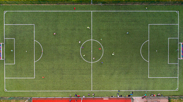 Aerial view of a green football pitch with players scattered across the field and white markings during a match Debrzno, Pomeranian Voivodeship, Poland.