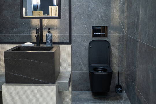 Contemporary bathroom interior featuring a black toilet, stone vessel sink and dark marble-effect wall tiles. Modern residential design, elegant fixtures, minimalist style, premium finishing materials