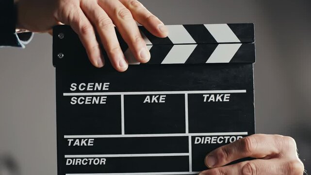 Closeup of a person holding a film clapperboard in front of the camera, ready for filming