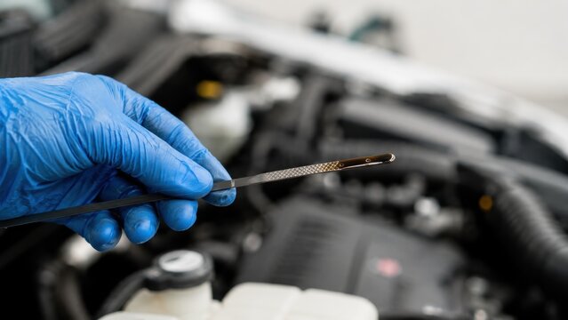 Mechanic Checking Engine Oil Level with Dipstick During Vehicle Maintenance Inspection
