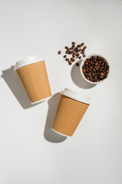 Roasted Coffee Beans and Takeaway Coffee Cups with on Light Background and soft shadows. Flat lay, top view