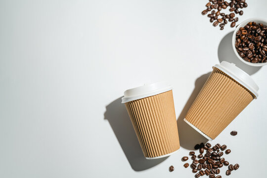 Roasted Coffee Beans and Takeaway Coffee Cups with on Light Background and soft shadows. Copy space