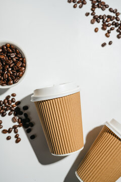 Takeaway coffee cups and roasted coffee beans on white background with copy space, flat lay