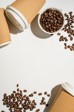 Takeaway coffee cups and roasted coffee beans on white background with copy space, flat lay