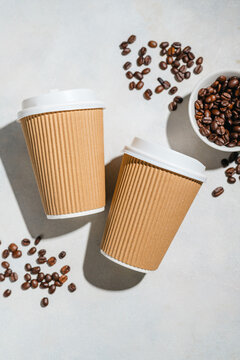 Roasted Coffee Beans and Takeaway Coffee Cups with on Light Background and soft shadows. Copy space
