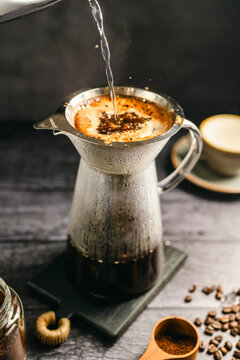 Pour hot water over coffee brewing with dripper and kettle, specialty coffee preparation, dark background, still life