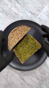 Spreading vibrant, herbaceous pesto on bread adds an instant, fresh Mediterranean flair. It transforms a simple slice of bread into a savory, aromatic snack or appetizer.