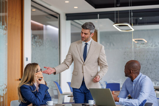 Business leader presenting ideas to a diverse team during a corporate meeting in a modern office boardroom