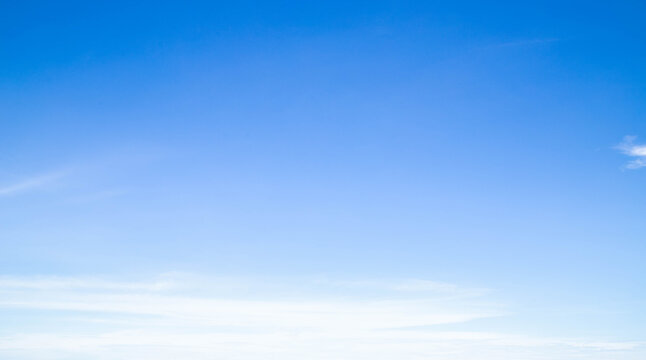 Wide panoramic blue sky with soft white clouds, clean bright sky background with copy space for website header or banner.