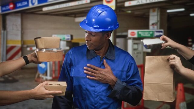 Man construction worker in blue hardhat holds hand to chest while multiple hands offer takeout food choices in building; gratitude choice sharing.