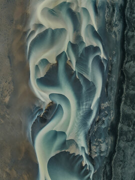 Aerial view of the intricate glacial river delta with turquoise water flowing through black volcanic sand at Solheimasandur, Vik, Myrdalshreppur, Iceland.