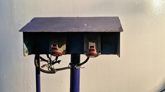 Outdoor Industrial Three Phase Power Distribution Box with Red CEE Sockets on Weathered Blue Metal Stand at Construction Site