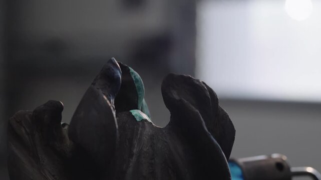 Exploring the process of patination on a metal sculpture in an indoor workshop setting during daylight