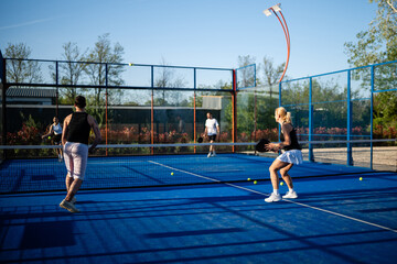 Naklejka premium Four friends playing padel tennis match outdoors